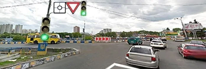 Ілюстрація до питання: Водій сірого автомобіля здійснює в’їзд на перехрестя з круговим рухом. Чи потрібно в такому випадку вмикати…